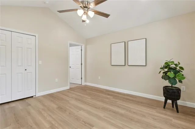 a view of a room with wooden floor and a chandelier fan