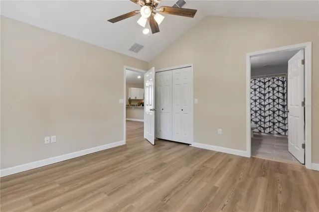 an empty room with wooden floor and ceiling fan