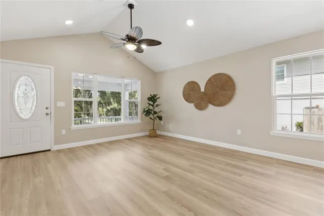 an empty room with wooden floor and windows