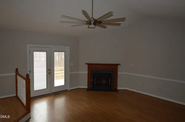 an empty room with wooden floor fan and windows
