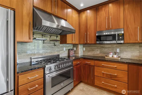 a kitchen with stainless steel appliances granite countertop wooden cabinets and a stove top oven