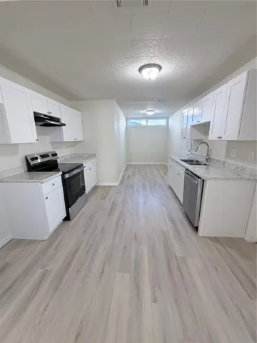 a kitchen with granite countertop a stove top oven and cabinets