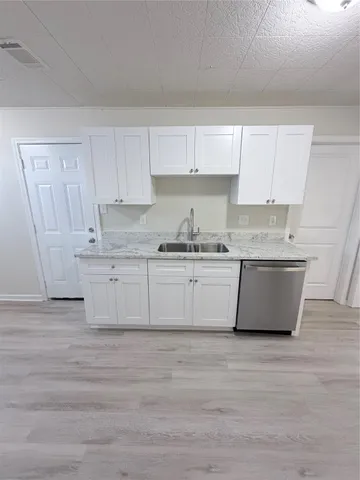 a white kitchen with granite countertop white cabinets and wooden floor