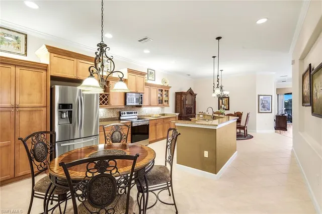 a kitchen with stainless steel appliances kitchen island granite countertop a table chairs and a refrigerator