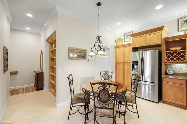 a kitchen with stainless steel appliances a refrigerator a stove a dining table and chairs with wooden floor