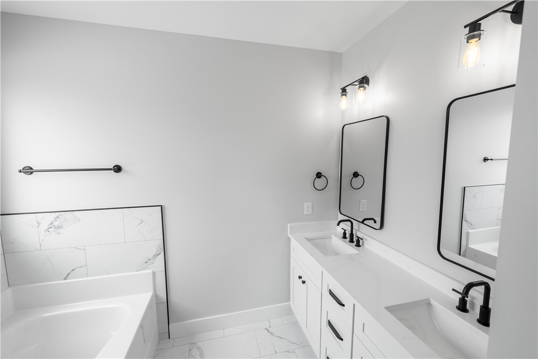 1619 Old Dobbins Bridge Road Townville, SC 29689 - Photo 24 of 34 This bright bathroom features dual vanities and a bathtub with elegant tile surround.