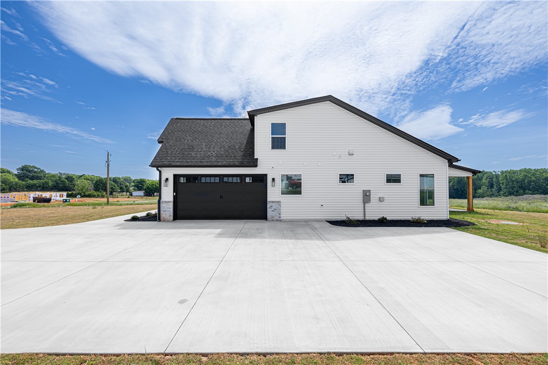 1619 Old Dobbins Bridge Road Townville, SC 29689 - Photo 33 of 34 This newly constructed residence showcases a modern facade with an attached garage and expansive concrete driveway.