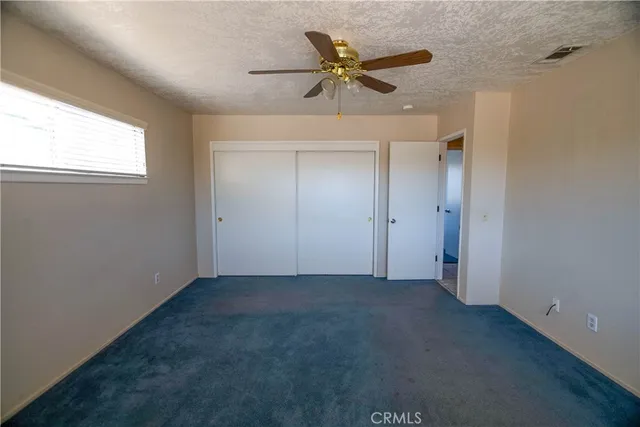an empty room with a ceiling fan and closet