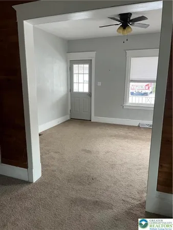 an empty room with windows and fan