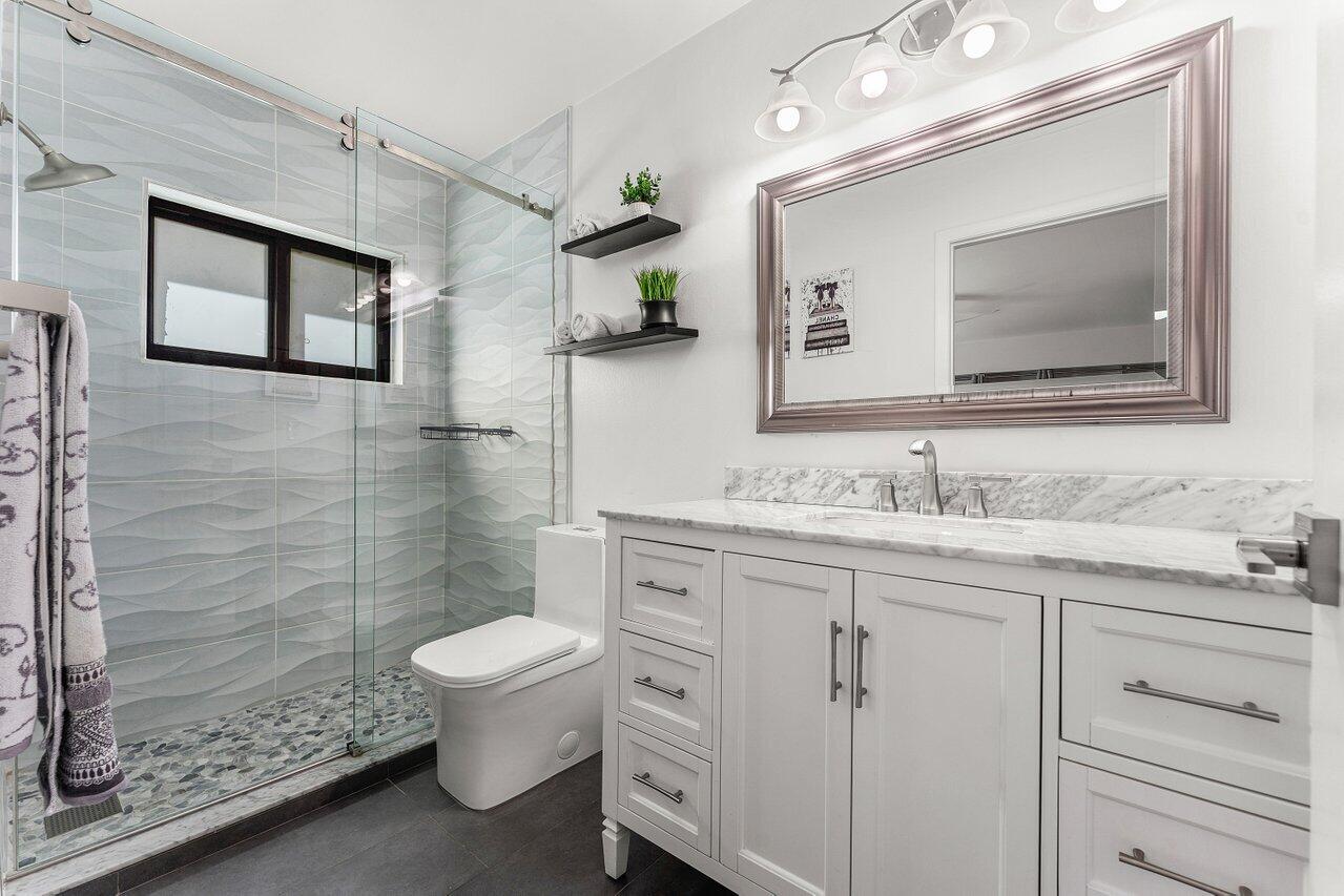 5300 Nesting Way, Unit A Delray Beach, FL 33484 - Photo 18 of 53 a bathroom with a toilet a sink a mirror and shower
