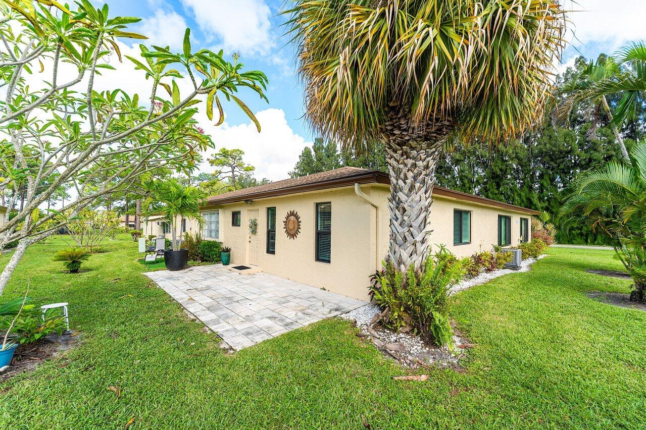 5300 Nesting Way, Unit A Delray Beach, FL 33484 - Photo 26 of 53 a front view of a house with a garden and trees