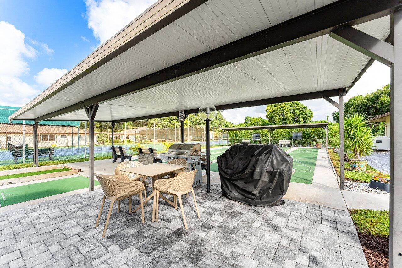 5300 Nesting Way, Unit A Delray Beach, FL 33484 - Photo 35 of 53 a view of a patio with a table chairs and a backyard