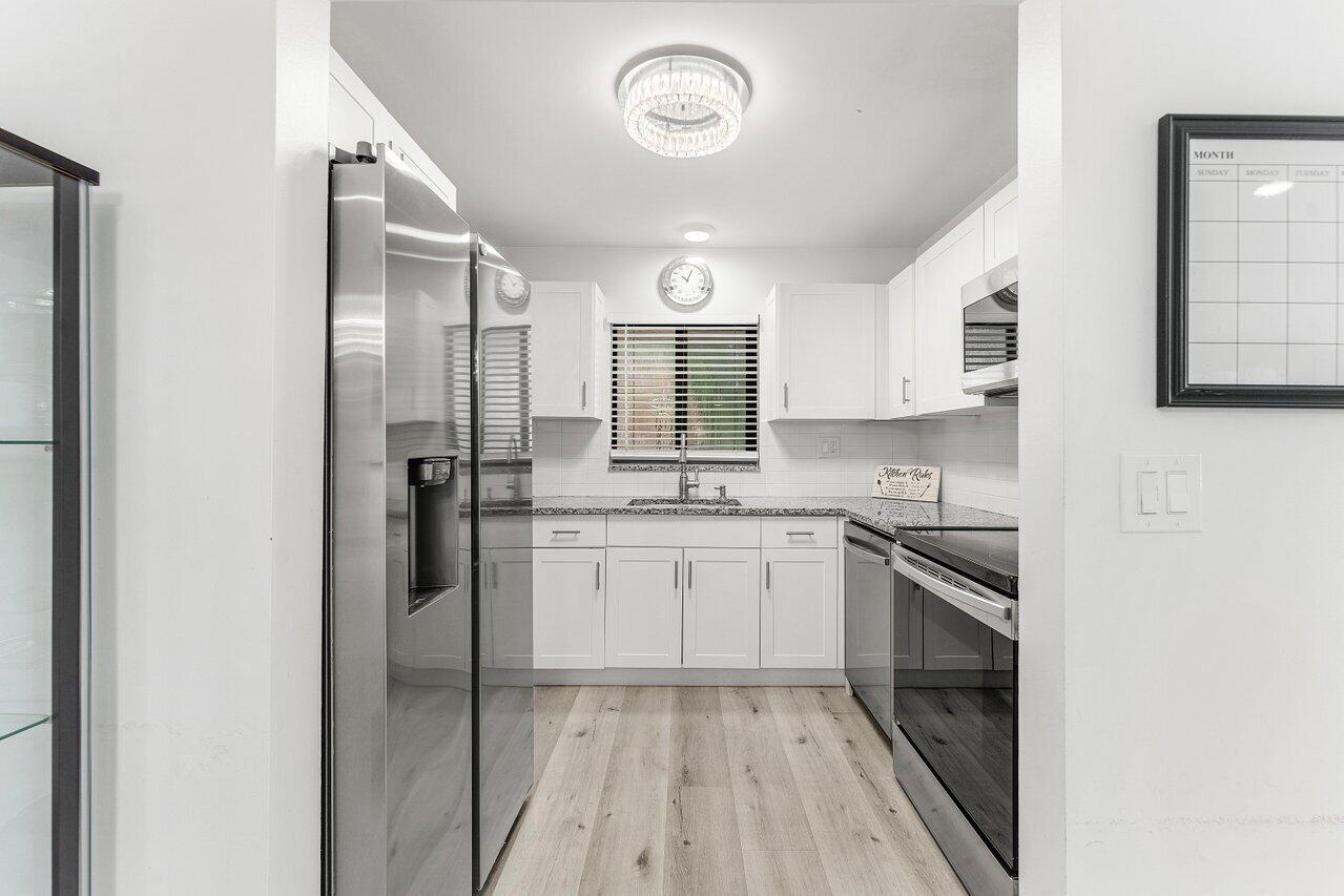5300 Nesting Way, Unit A Delray Beach, FL 33484 - Photo 6 of 53 a kitchen with stainless steel appliances granite countertop a stove and a refrigerator