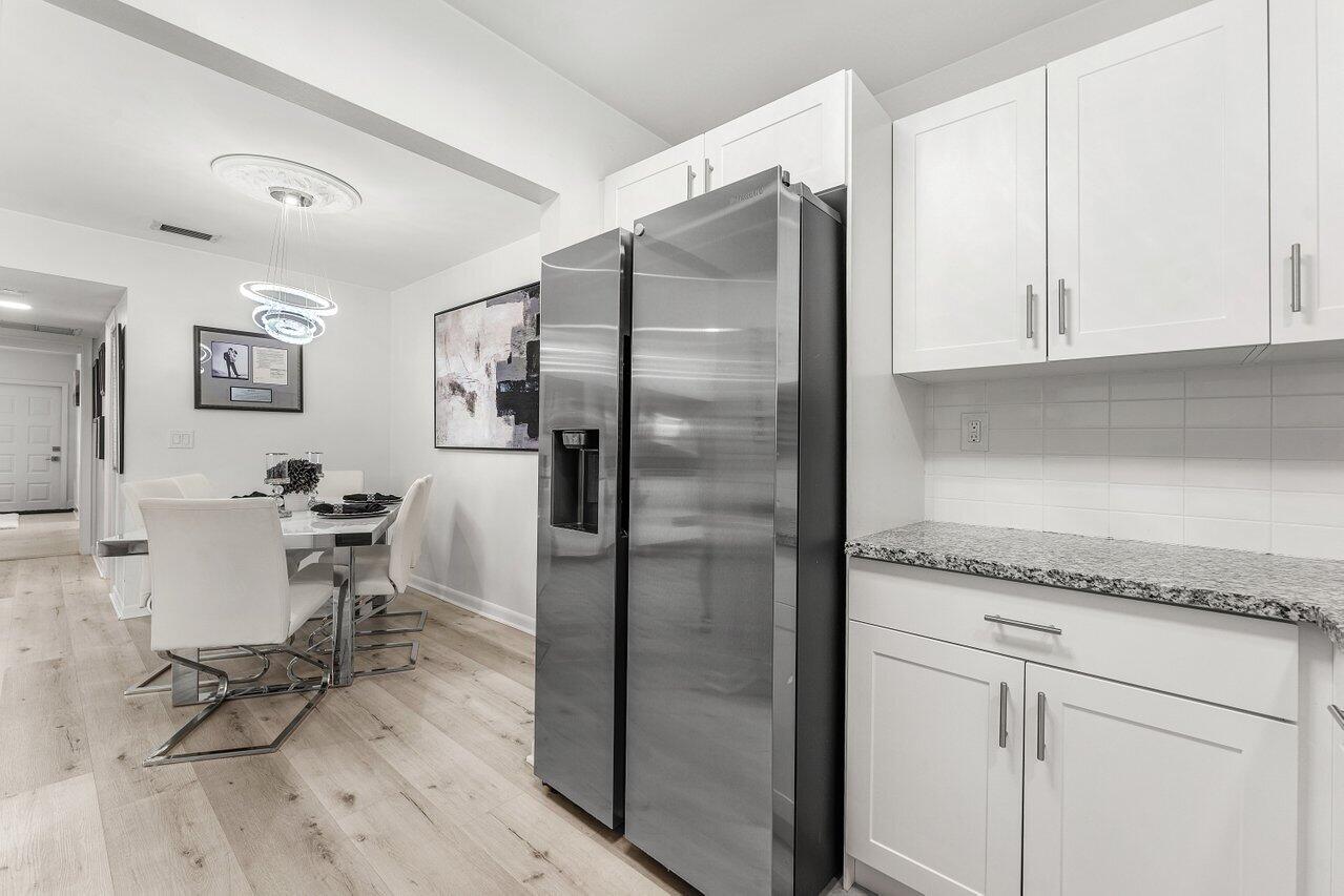 5300 Nesting Way, Unit A Delray Beach, FL 33484 - Photo 9 of 53 a kitchen with stainless steel appliances granite countertop a refrigerator and white cabinets