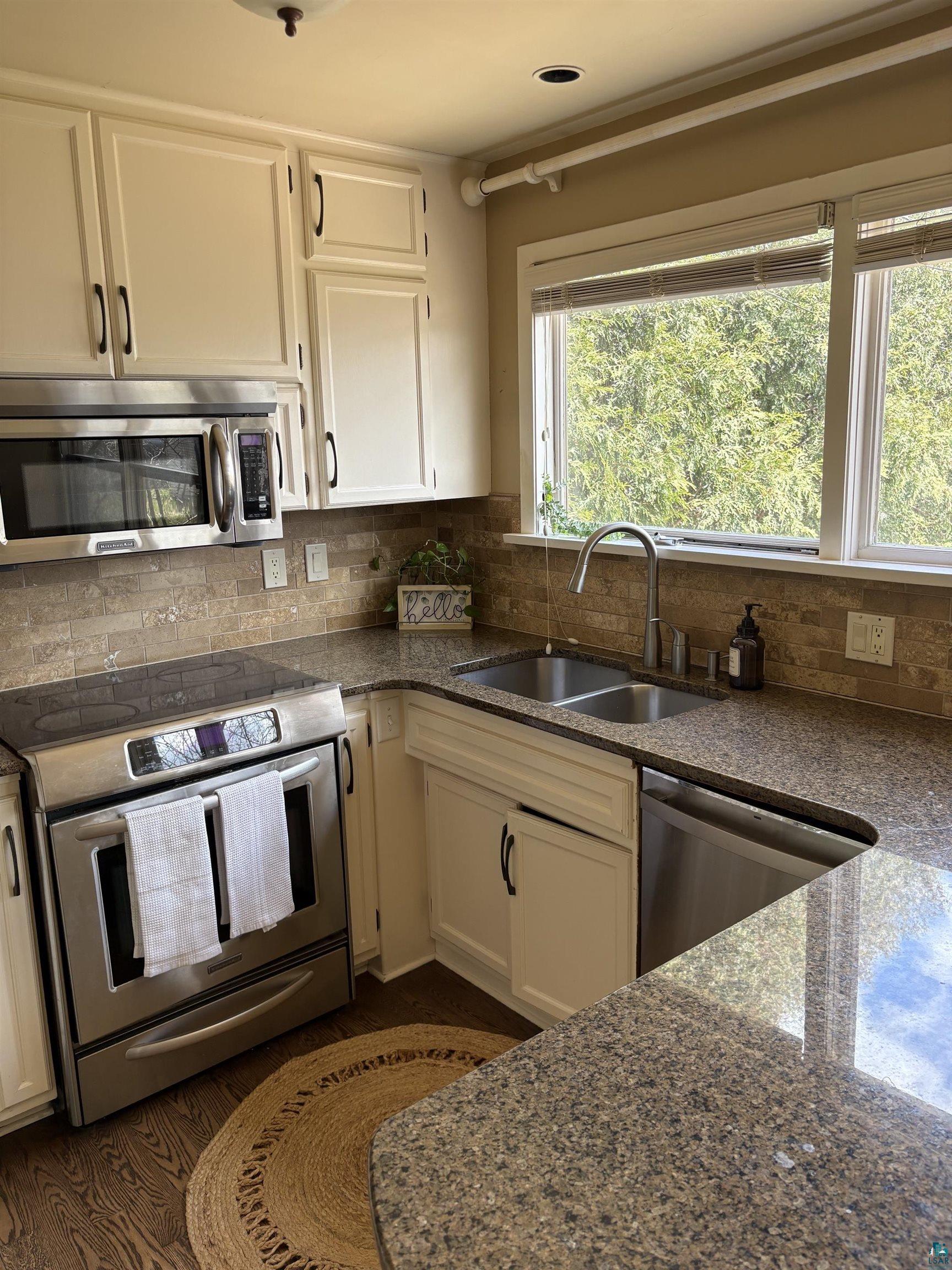 1918 West Kent Road Duluth, MN 55812 - Photo 8 of 42 Kitchen featuring wood-finish flooring, white cabinetry with dark hardware, a stainless steel oven/range, a stainless steel microwave, and a double basin stainless steel sink with a high-arc faucet