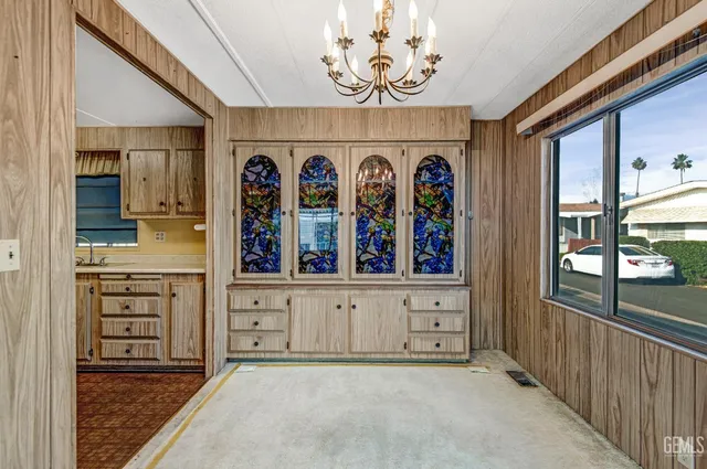 a view of an empty room with a window and a kitchen