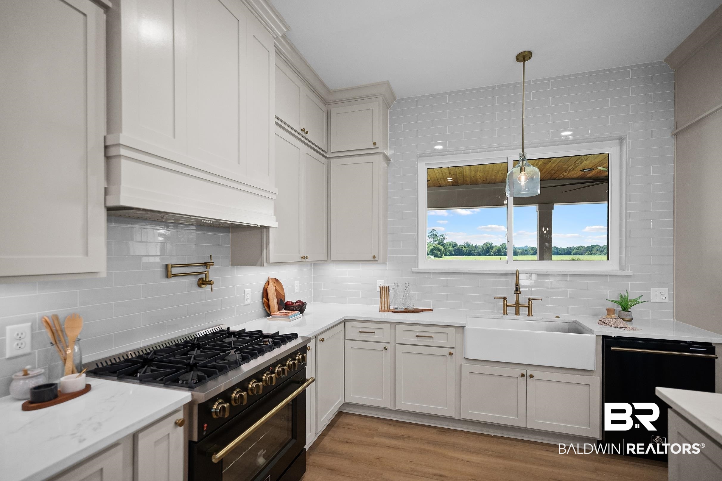13111 Gopher Court Elberta, AL 36530 - Photo 11 of 41 Gourmet kitchen featuring a large professional-grade range, white subway tile backsplash, white shaker-style cabinetry, quartz countertops, and a farmhouse sink with brass fixtures