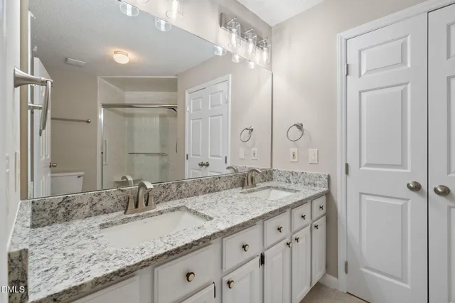 a bathroom with a granite countertop sink a toilet and a mirror
