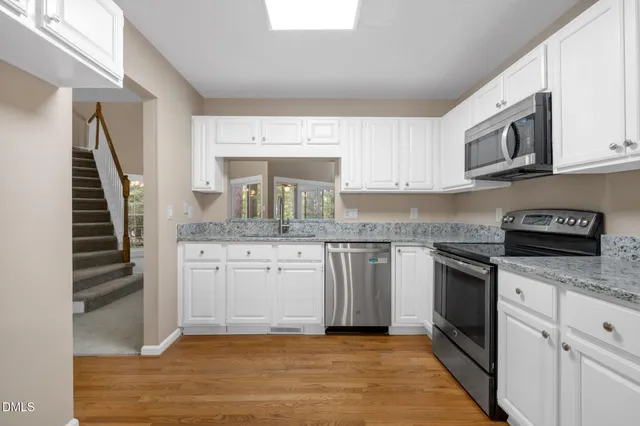 a kitchen with granite countertop wooden cabinets stainless steel appliances and a window