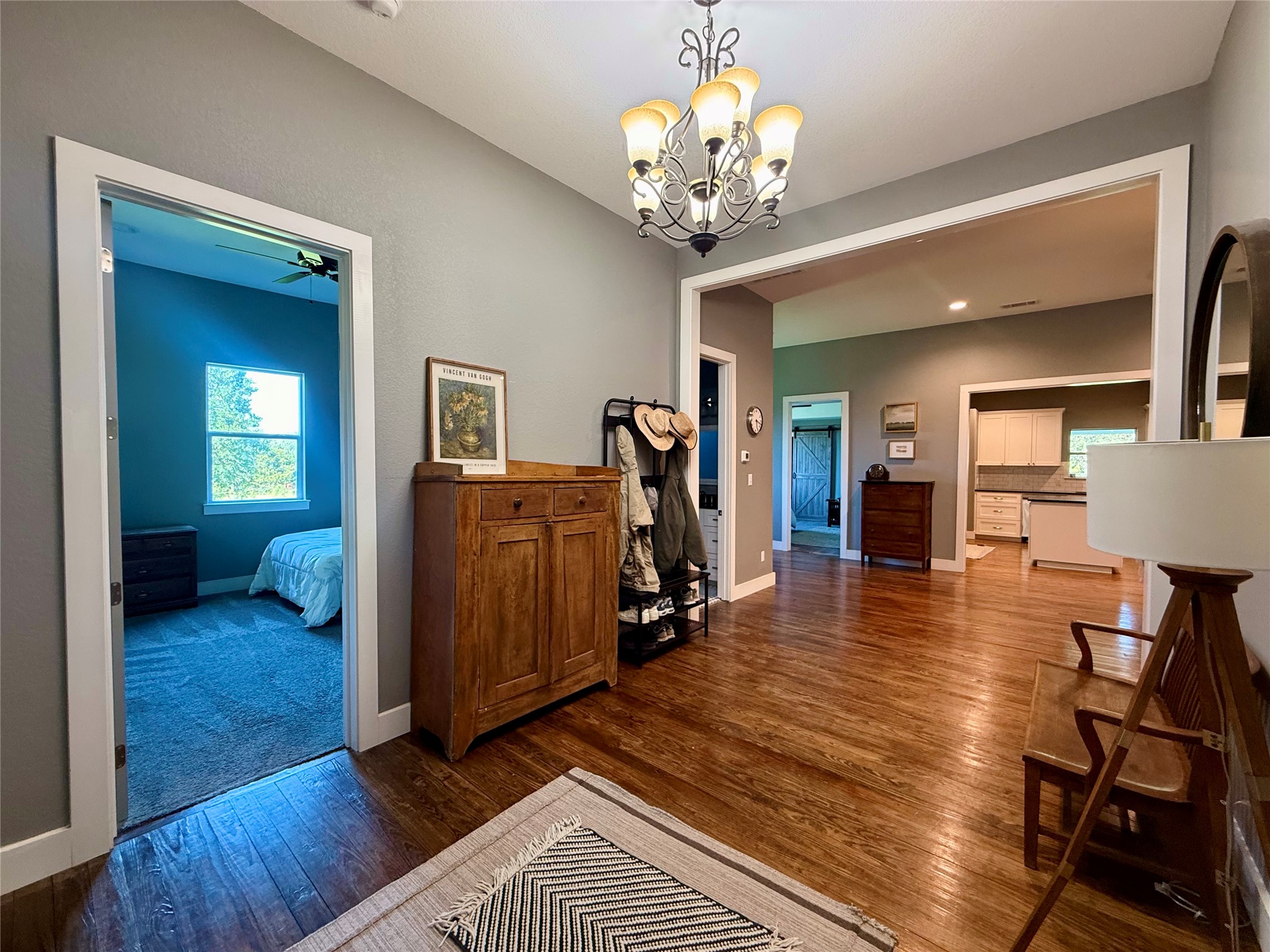 739 Pleasant Grove Road Elgin, TX 78621 - Photo 4 of 29 Interior hallway featuring wood-finish flooring, a decorative chandelier, and light gray wall paint