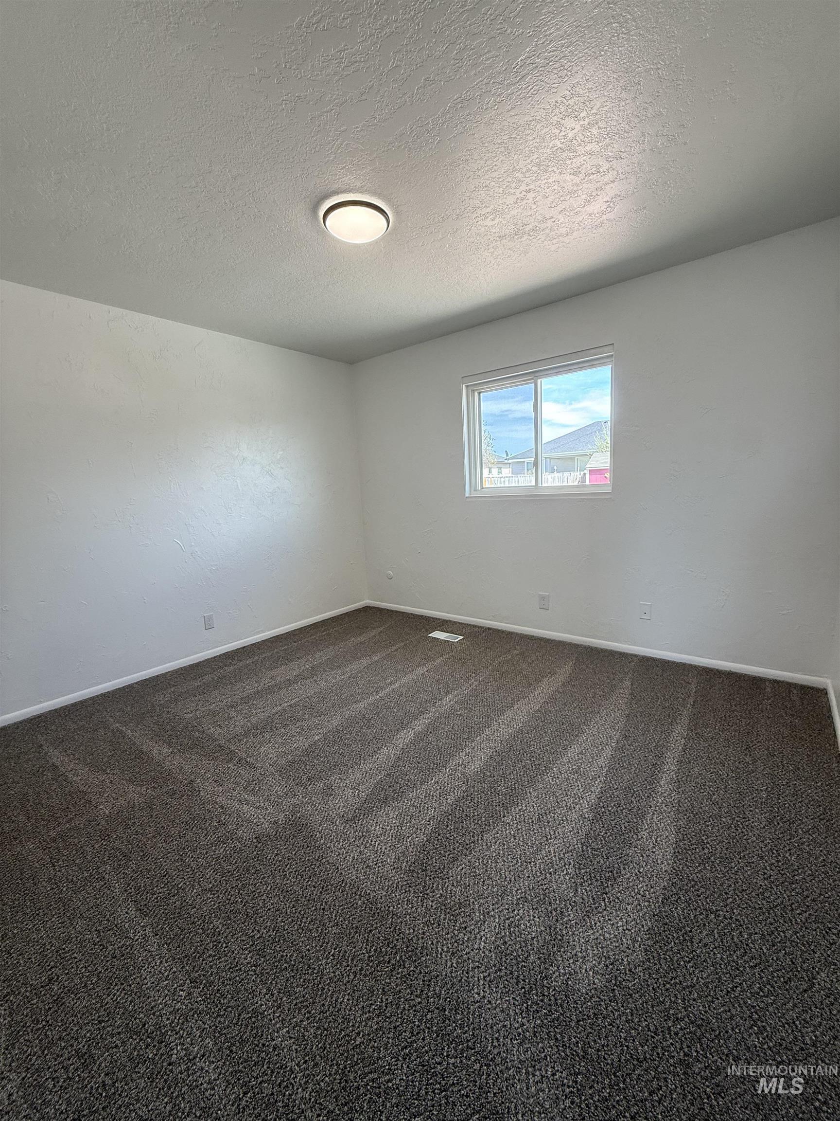709 Locust Street Kimberly, ID 83341 - Photo 12 of 13 Spare room featuring dark colored carpet and a textured ceiling