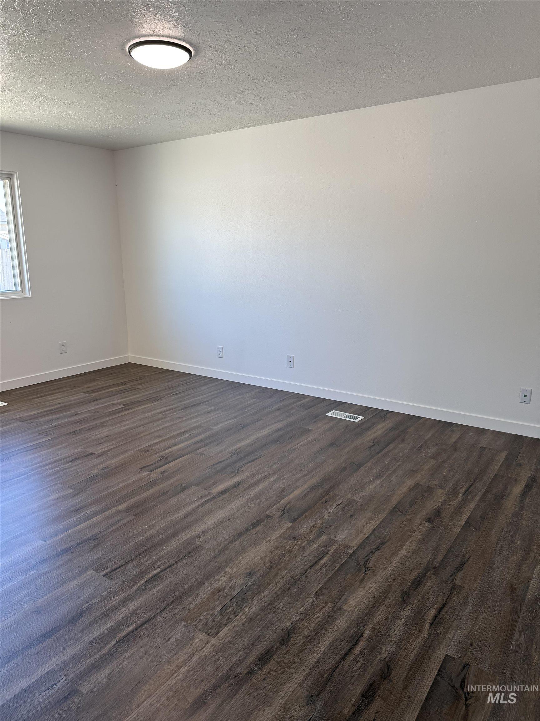 709 Locust Street Kimberly, ID 83341 - Photo 4 of 13 Spare room with dark wood-style floors and a textured ceiling