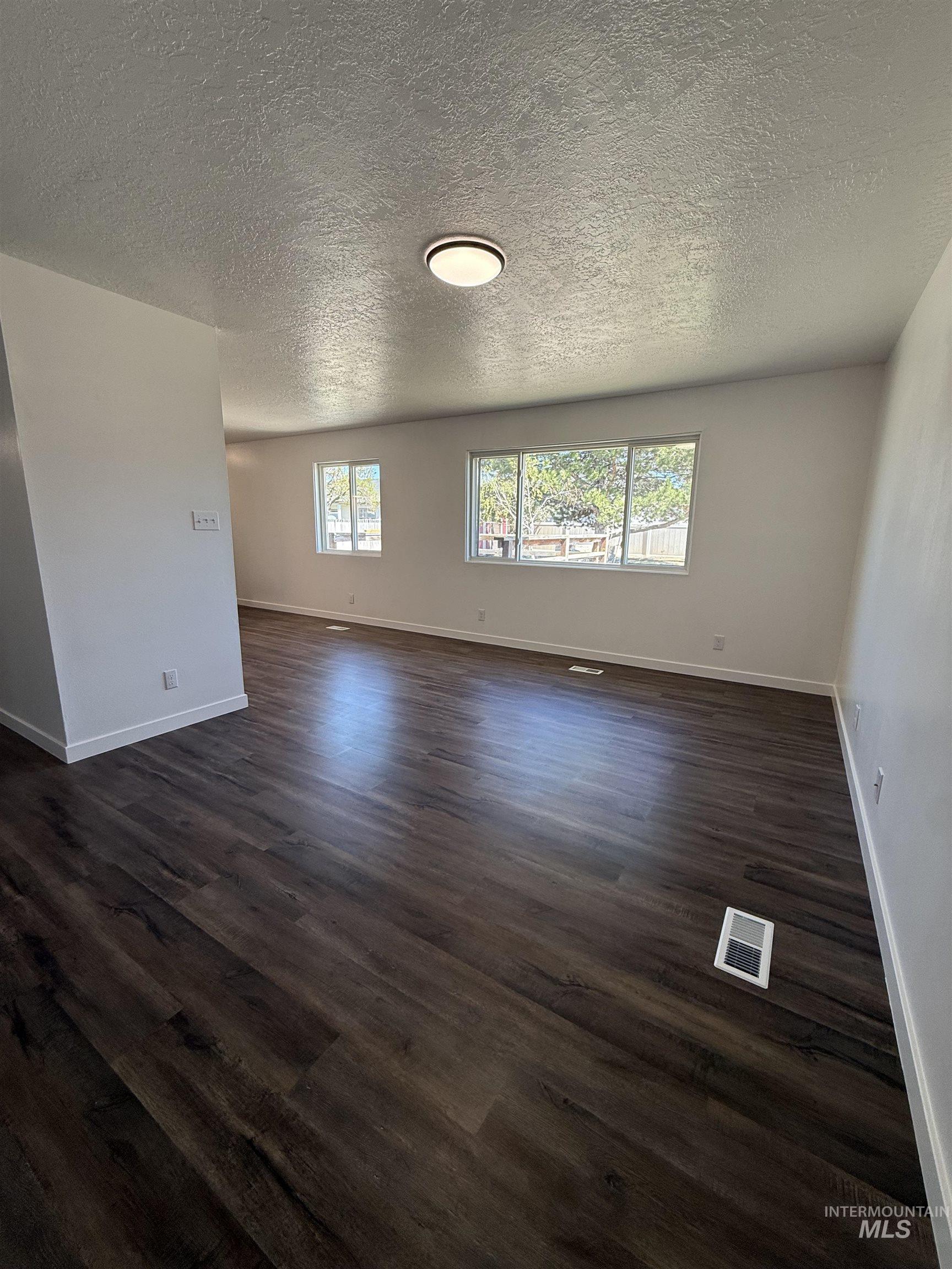 709 Locust Street Kimberly, ID 83341 - Photo 5 of 13 Unfurnished room featuring dark wood finished floors and a textured ceiling