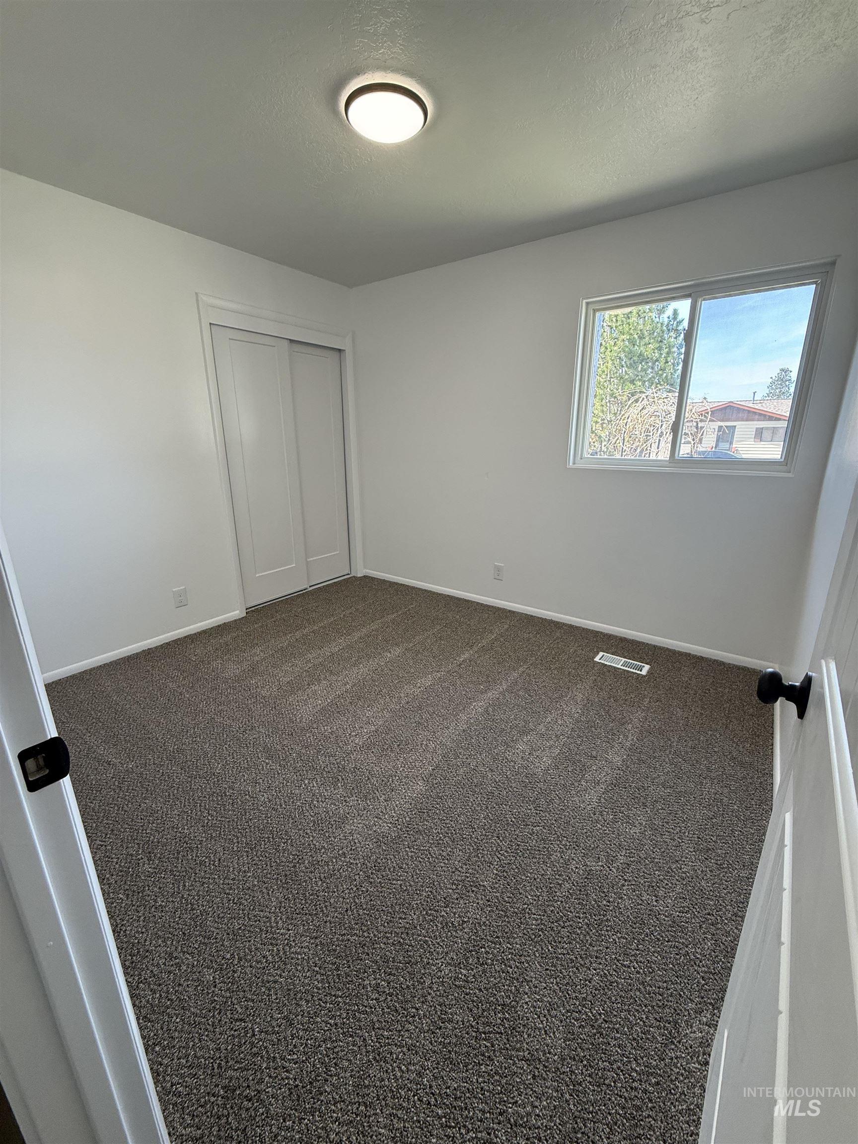 709 Locust Street Kimberly, ID 83341 - Photo 9 of 13 Unfurnished bedroom with dark carpet, a textured ceiling, and a closet