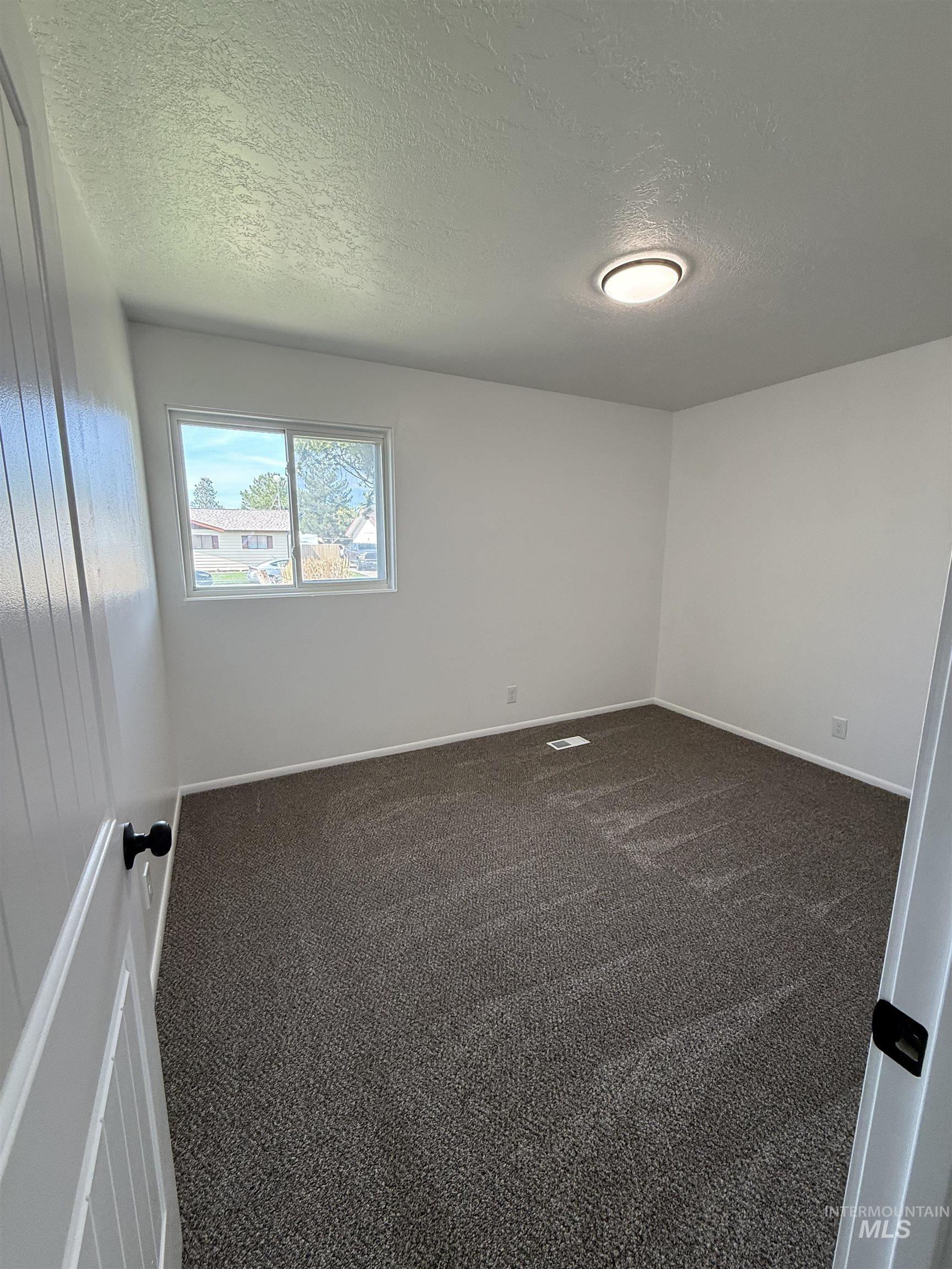 709 Locust Street Kimberly, ID 83341 - Photo 10 of 13 Spare room featuring a textured ceiling and dark carpet