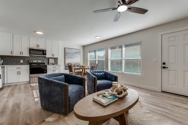 a living room with furniture kitchen view and a window