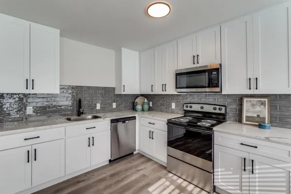 a kitchen with stainless steel appliances white cabinets granite counter tops and a sink