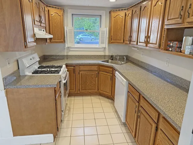 a kitchen with a sink a stove cabinets and a window