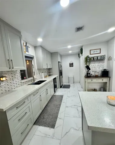 a large kitchen with kitchen island a large counter top stainless steel appliances and cabinets