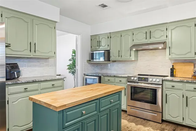 a kitchen with stainless steel appliances granite countertop a stove a sink and a microwave