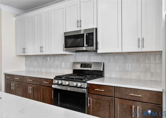 a kitchen with stainless steel appliances granite countertop grey cabinets a stove top oven and microwave