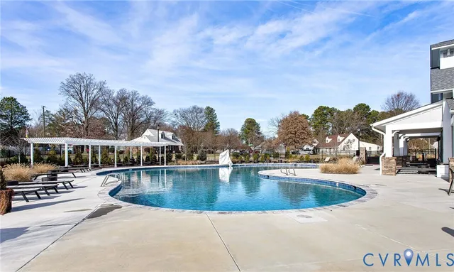 a view of swimming pool with outdoor seating and trees in the background