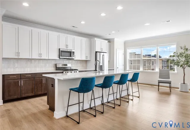 a kitchen with stainless steel appliances granite countertop a stove a sink a microwave a dining table and chairs with wooden floor