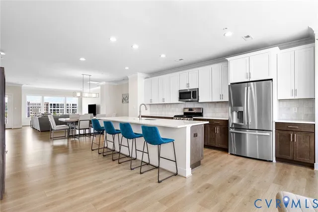 a kitchen with kitchen island granite countertop stainless steel appliances refrigerator cabinets dining table and chairs