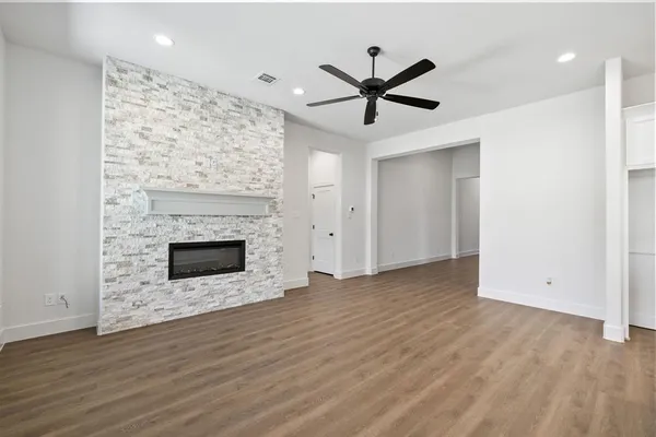 a view of a livingroom with wooden floor a ceiling fan and windows