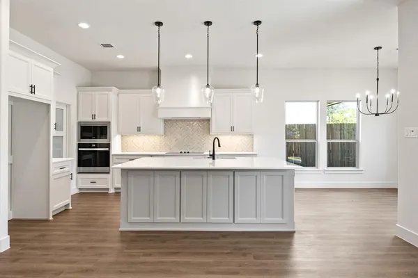 a open kitchen with stainless steel appliances granite countertop a sink a oven and a wooden floors