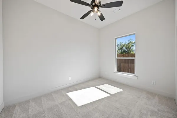 an empty room with a window and a ceiling fan