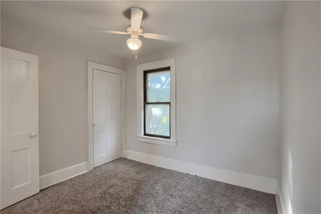 an empty room with a chandelier fan and windows