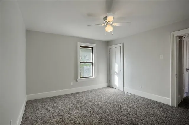 an empty room with windows and fan