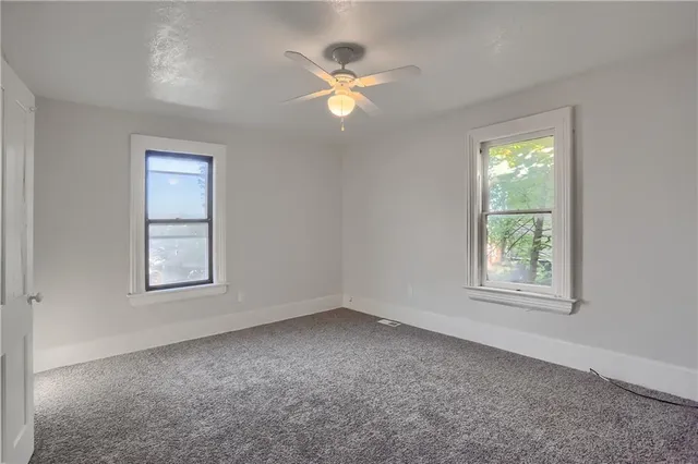 an empty room with a window and a ceiling fan
