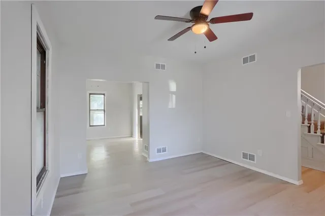 an empty room with chandelier fan and windows