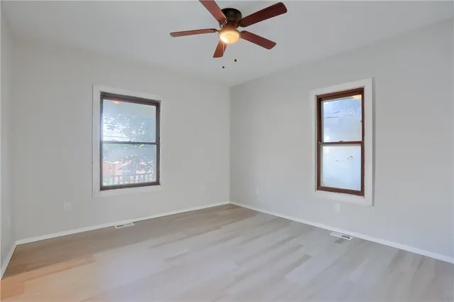 an empty room with a window and a ceiling fan