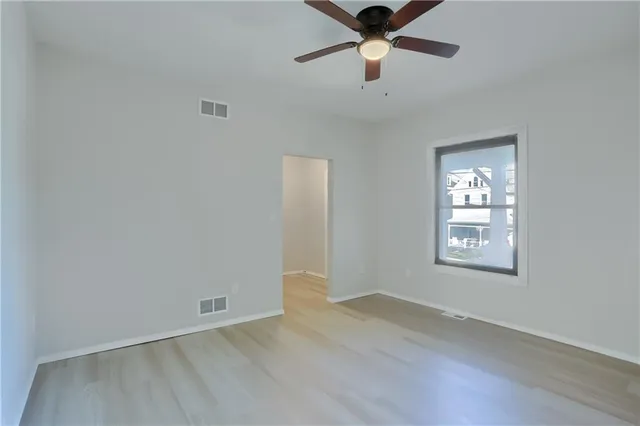 an empty room with wooden floor and windows