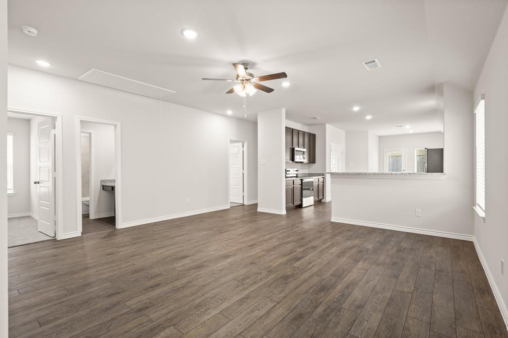 1507 Romans Road Ennis, TX 75119 - Photo 8 of 19 a view of an empty room with wooden floor and a kitchen