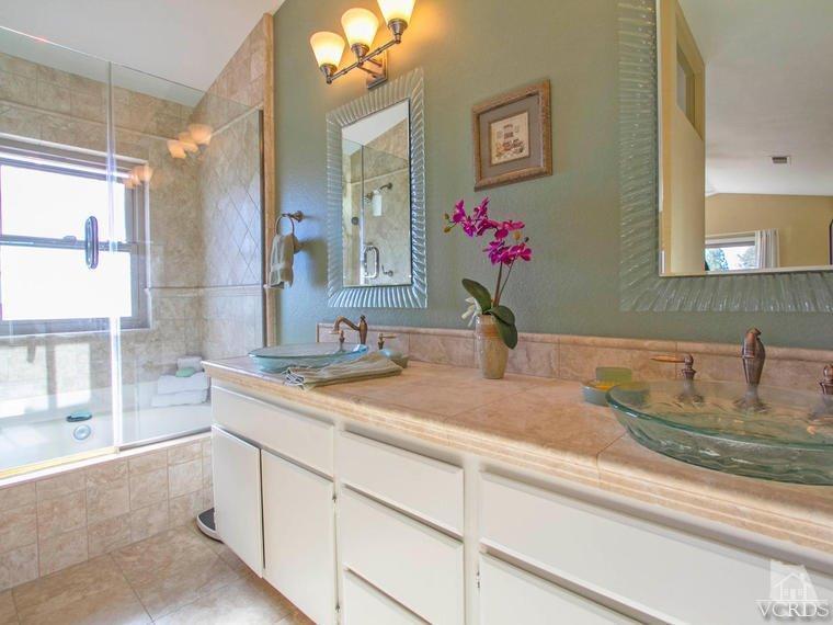 15310 Rains Court Moorpark, CA 93021 - Photo 20 of 29 a bathroom with a granite countertop sink a large mirror and a shower