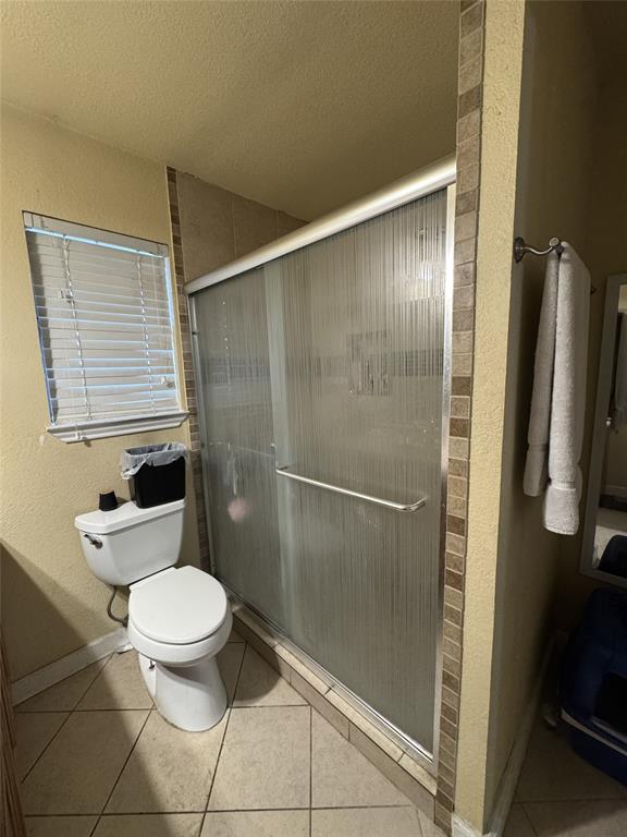 636 East Kempner Street Mabank, TX 75147 - Photo 26 of 28 Bathroom featuring a tiled shower enclosure with a sliding frosted glass door, a window with blinds, and ceramic tile flooring
